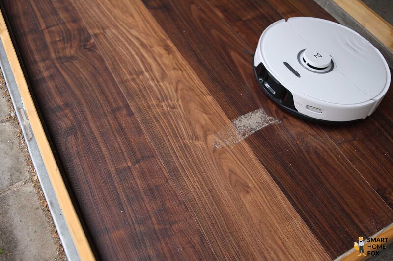 Roborock S8 Pro Ultra reinigt Sand im Saugtest auf einem Hartboden.